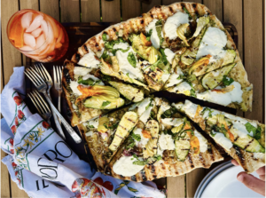Pizza with grill marks rounds of white cheese and yellow zucchini flowers